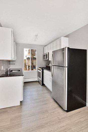 A kitchen with a black refrigerator and white cabinets
